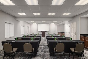 A conference room with tables, chairs, a projector screen, and water bottles. - Homewood Suites by Hilton Jacksonville Deerwood Park (Jacksonville)
