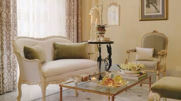 A classic room with a white sofa, a glass coffee table, and a decorative table with candles.