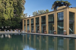 A modern building with a pool, large windows, and outdoor seating.