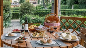 A picnic table set outdoors with food, drinks, and a basket of bread.