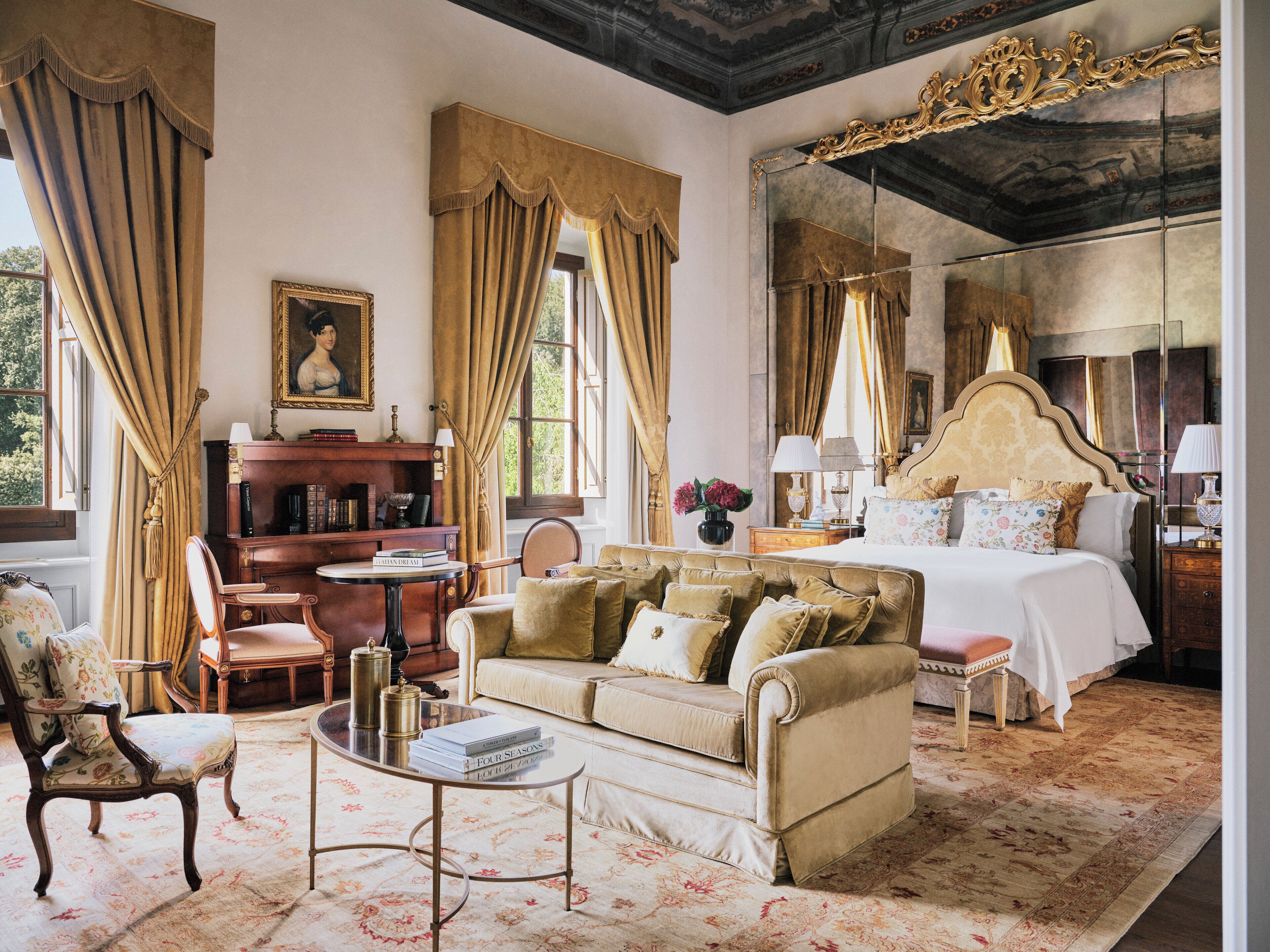 A classic hotel room with a large bed, a sofa, a desk, and a chair.