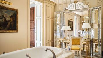 Ein luxuriöses Badezimmer mit einer großzügigen Badewanne, verzierten Spiegeln und einem klassischen Sessel.