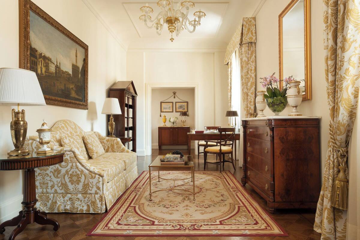 Una habitación con sofá, mesa de centro, aparador de madera, candelabro y un cuadro en la pared.