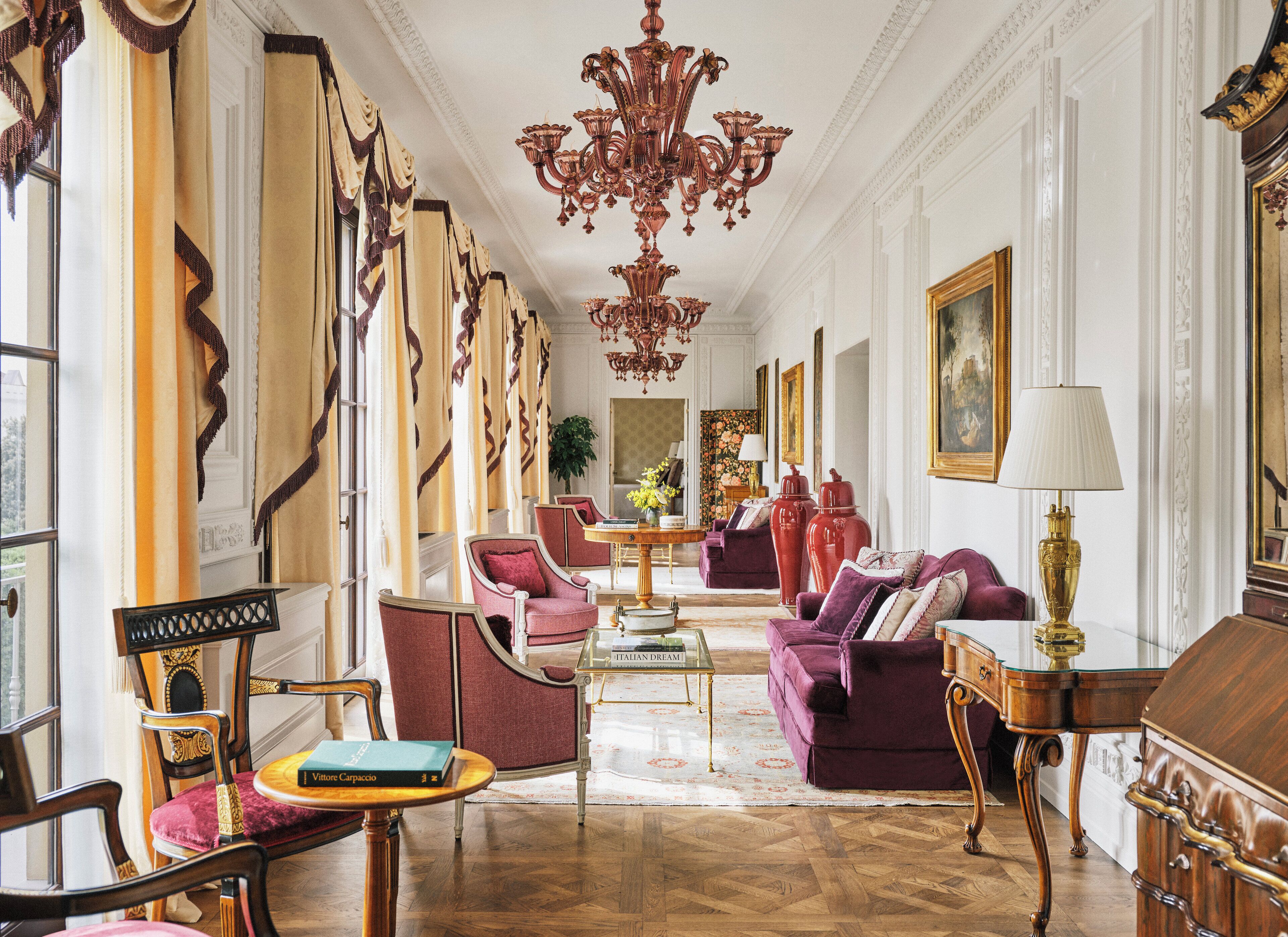 A luxurious living room with ornate furniture, a chandelier, and a large window with curtains.