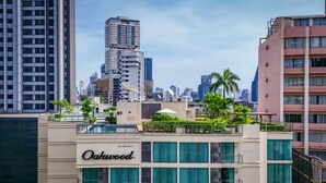 A hotel with a rooftop garden, multiple floors, and a city skyline in the background.