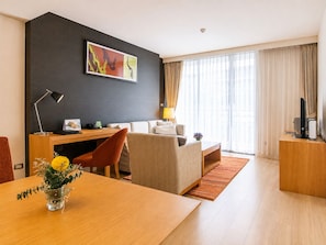 A modern hotel room with a desk, a sofa, a dining table, and a large window with curtains. - Oakwood Residence Sukhumvit 24 Bangkok (Bangkok)