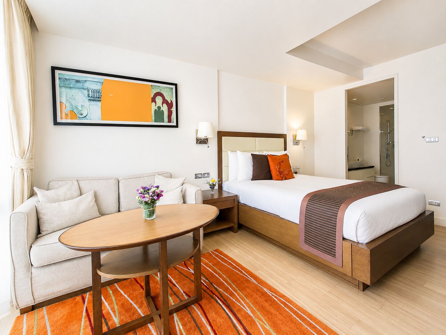 Une chambre d’hôtel avec un lit, un canapé, une table et un tableau au mur.