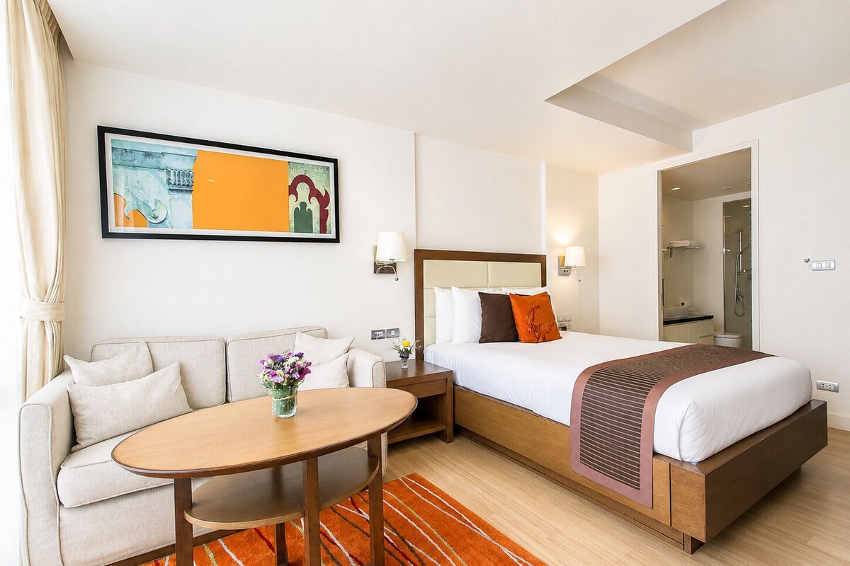 Una habitación de hotel con una cama, un sofá, una mesa y un cuadro en la pared.