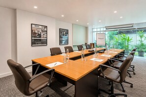 Ein Konferenzraum mit einem langen Tisch, Stühlen und einer Wandtafel.