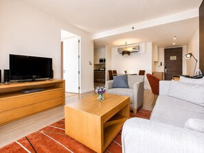 Una sala de estar moderna con televisor de pantalla plana, mueble de entretenimiento de madera, sofá gris y una mesa de centro.