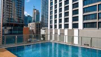 A rooftop swimming pool with a view of high-rise buildings.