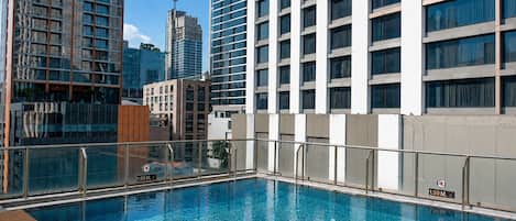 A rooftop swimming pool with a view of high-rise buildings.