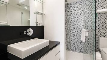 A modern bathroom with a white sink, black countertop, and a shower with mosaic tiles.
