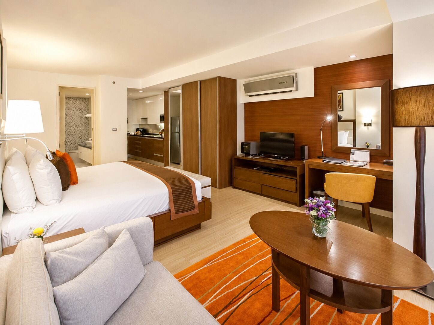 A hotel room with a bed, a desk, a TV, a laptop, a chair, and a dining table.