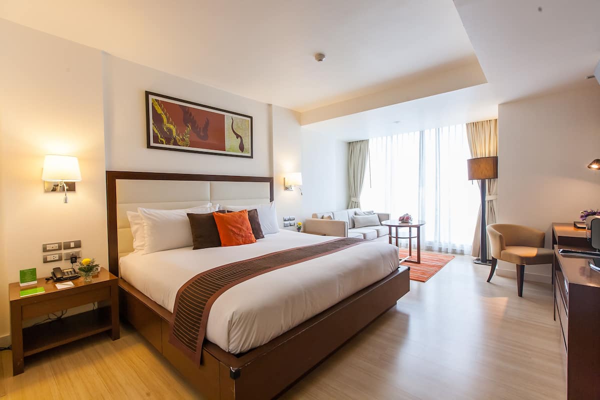A hotel room with a large bed, bedside tables, a desk, and a chair.