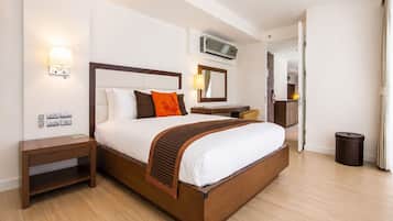 A hotel room with a large bed, bedside tables, a desk, and a trash bin.