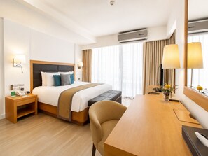 Une chambre d’hôtel équipée d’un lit, d’une table de chevet, d’une lampe, d’un bureau, d’une chaise et d’un appareil de climatisation.