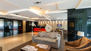 A modern lobby with a reception desk, seating area, and a television screen.