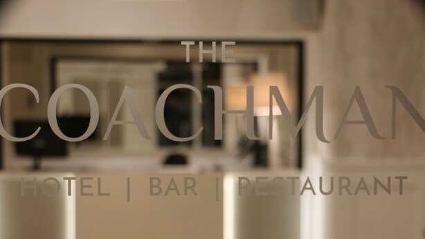 A blurred interior of a hotel, bar, and restaurant with the name "The Coachman" visible. - Coachman Hotel (Glasgow)