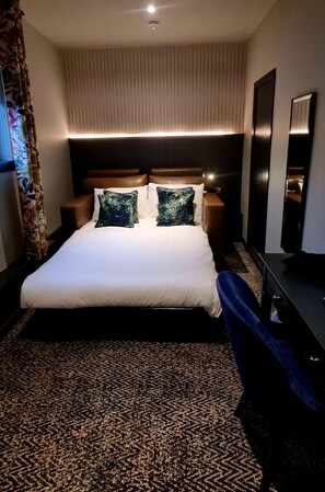 A hotel room with a large bed, two nightstands, a flat-screen TV, and a patterned carpet. - Coachman Hotel (Glasgow)