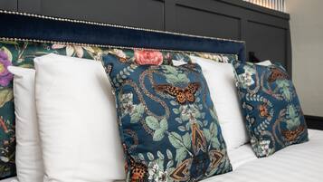 A bed with white linens and decorative pillows with floral patterns.