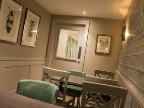 A dining area with a wooden table and chairs, framed artwork on the walls, and a door with a mirror. - Coachman Hotel (Glasgow)