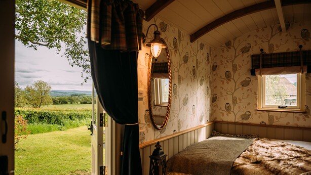 A cozy bedroom with a large window, a wooden headboard, and a view of the garden. - The Red Pump Inn (Clitheroe)