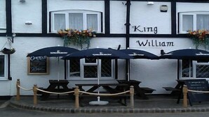 Un pub llamado 'King William' con terraza y macetas de flores.