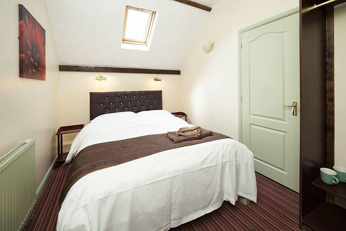 A bedroom with a bed, a window, a door, and a radiator.