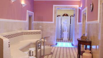 Bathroom features a bathtub and separate shower area with geometric tile pattern and wall-mounted lighting.
