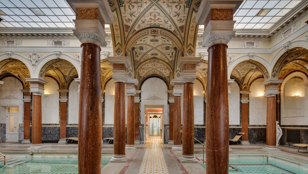A grand hall with a central pool, ornate columns, and a detailed ceiling.
