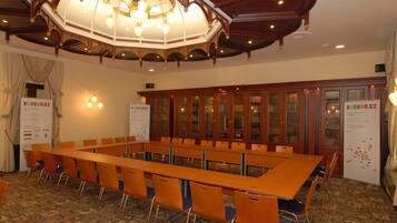 A conference room with a long table and chairs, wooden cabinets, and a decorative ceiling.