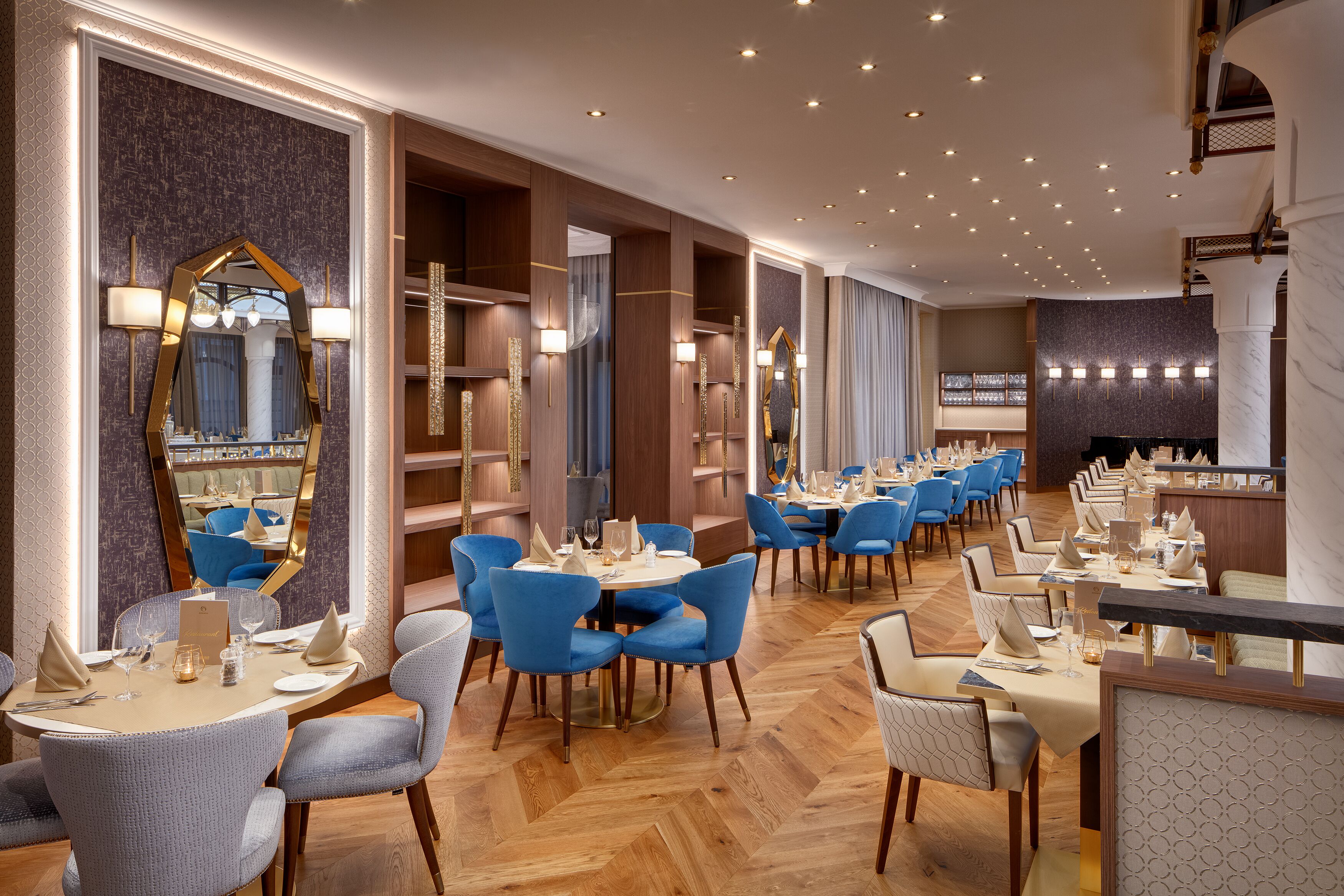 Un restaurante con varias mesas, sillas azules y una zona de bar.