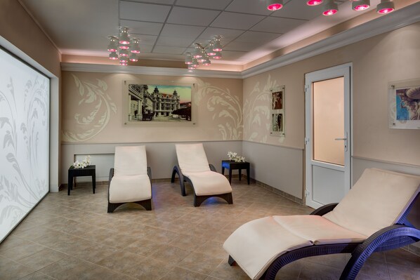A room with three reclining chairs, a small table with flowers, and a door.