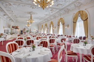 Un gran salón de banquetes con mesas redondas, sillas blancas y tapicería a rayas rojas y blancas.