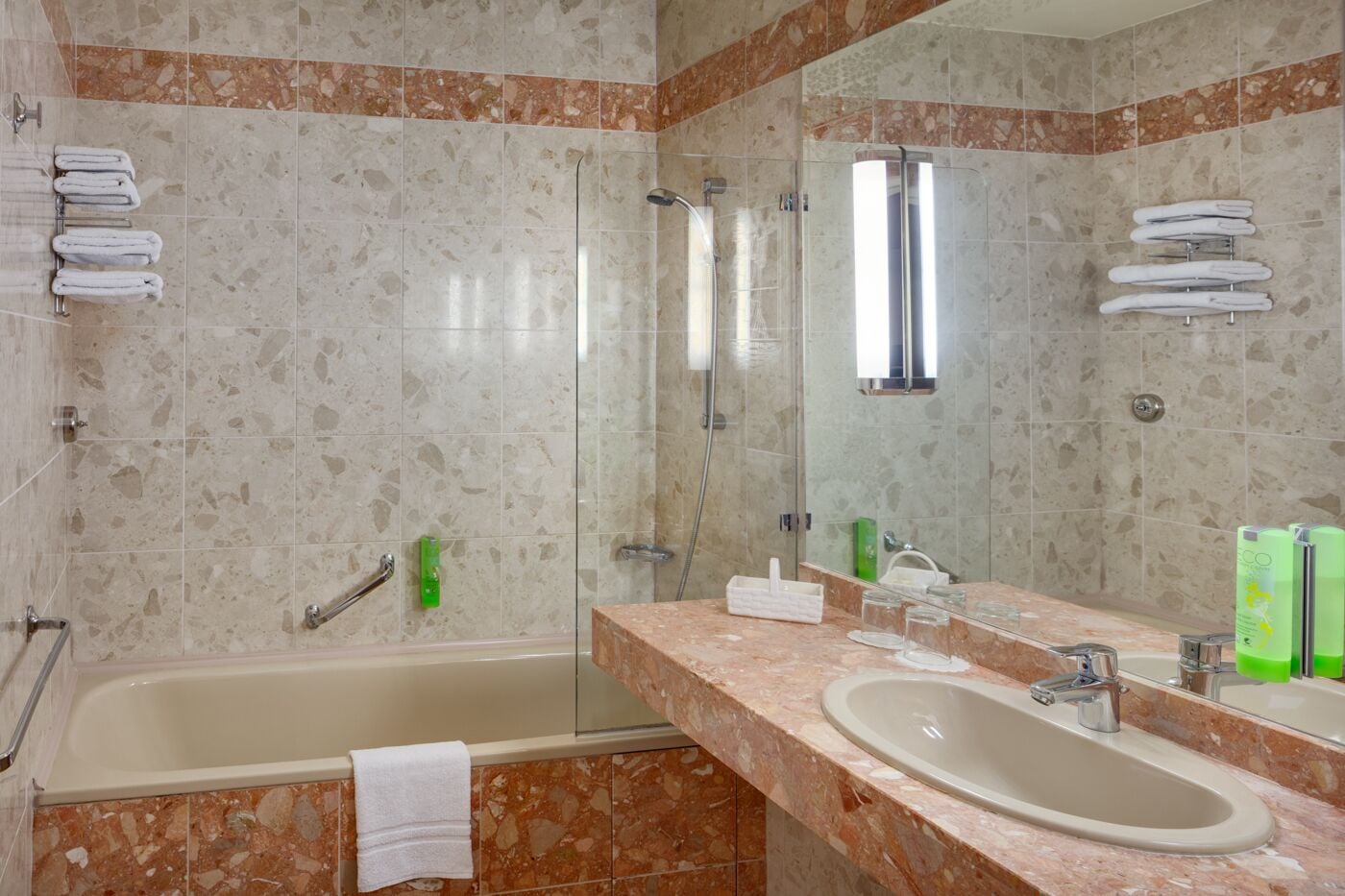 Een badkamer met een badkuip, douche, wastafel en een grote spiegel.