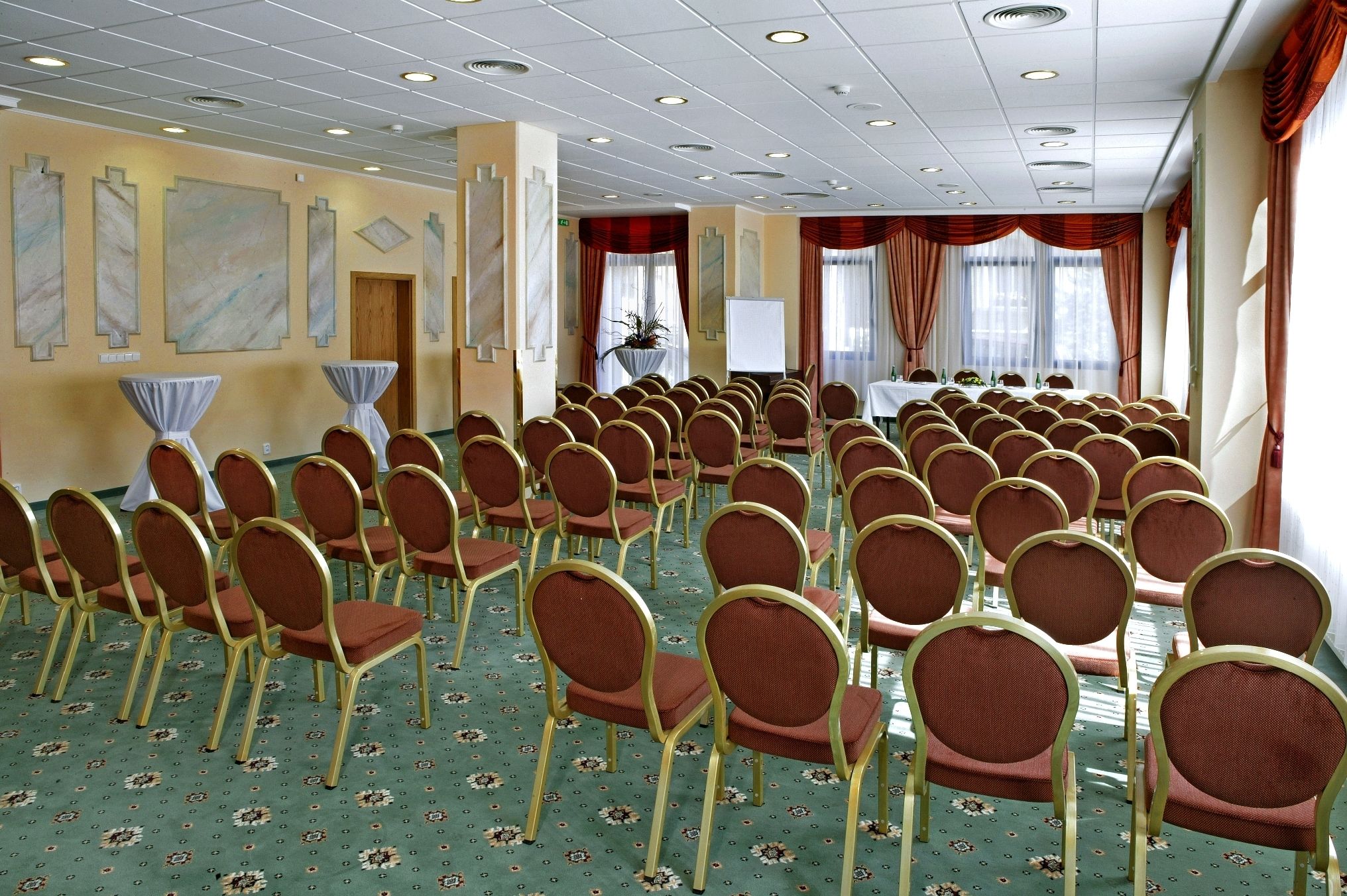 A conference room with rows of chairs, a whiteboard, and a table with chairs.