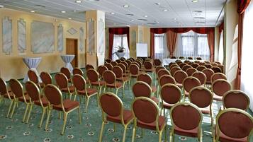 A conference room with rows of chairs, a whiteboard, and a table with chairs.