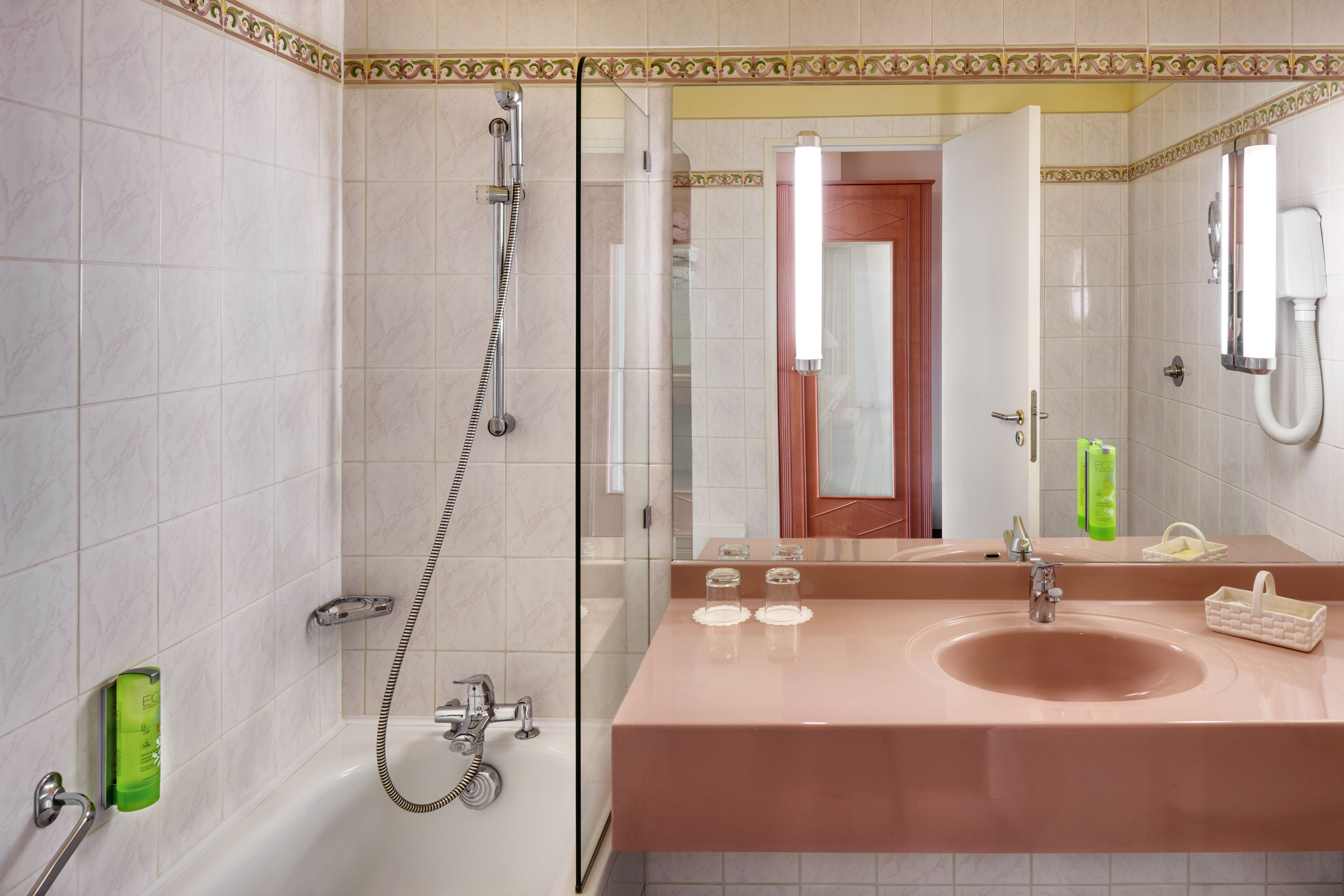 Ein Badezimmer mit einem großen Spiegel, einem Waschbecken und einer Dusche.