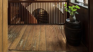A wooden spiral staircase in a hallway with a wooden railing, a potted plant, and a window with green-tinted glass. - Hotel Vinhuset (Naestved)