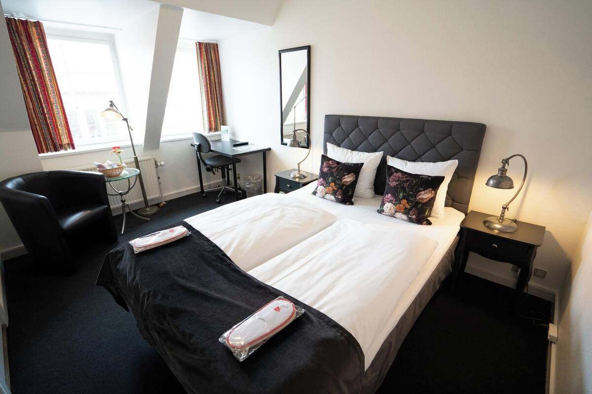 Una habitación de hotel con una cama grande, un escritorio, una silla y una mesita.