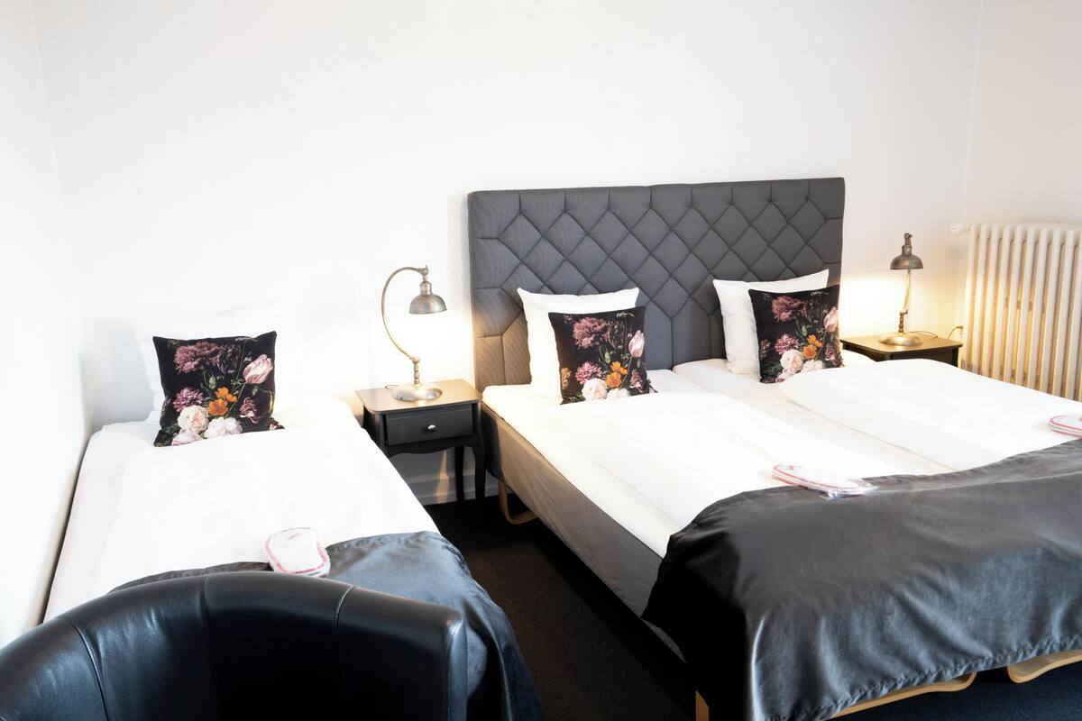 Una habitación de hotel con dos camas, una mesita de noche, una lámpara y una silla.