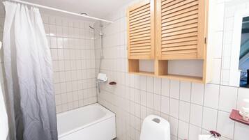 A bathroom with a bathtub, a shower, and wooden cabinets above the sink.