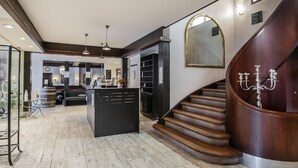A spacious lobby with a central reception desk, a staircase with a wooden finish, and a large mirror on the wall. - Hotel Vinhuset (Naestved)