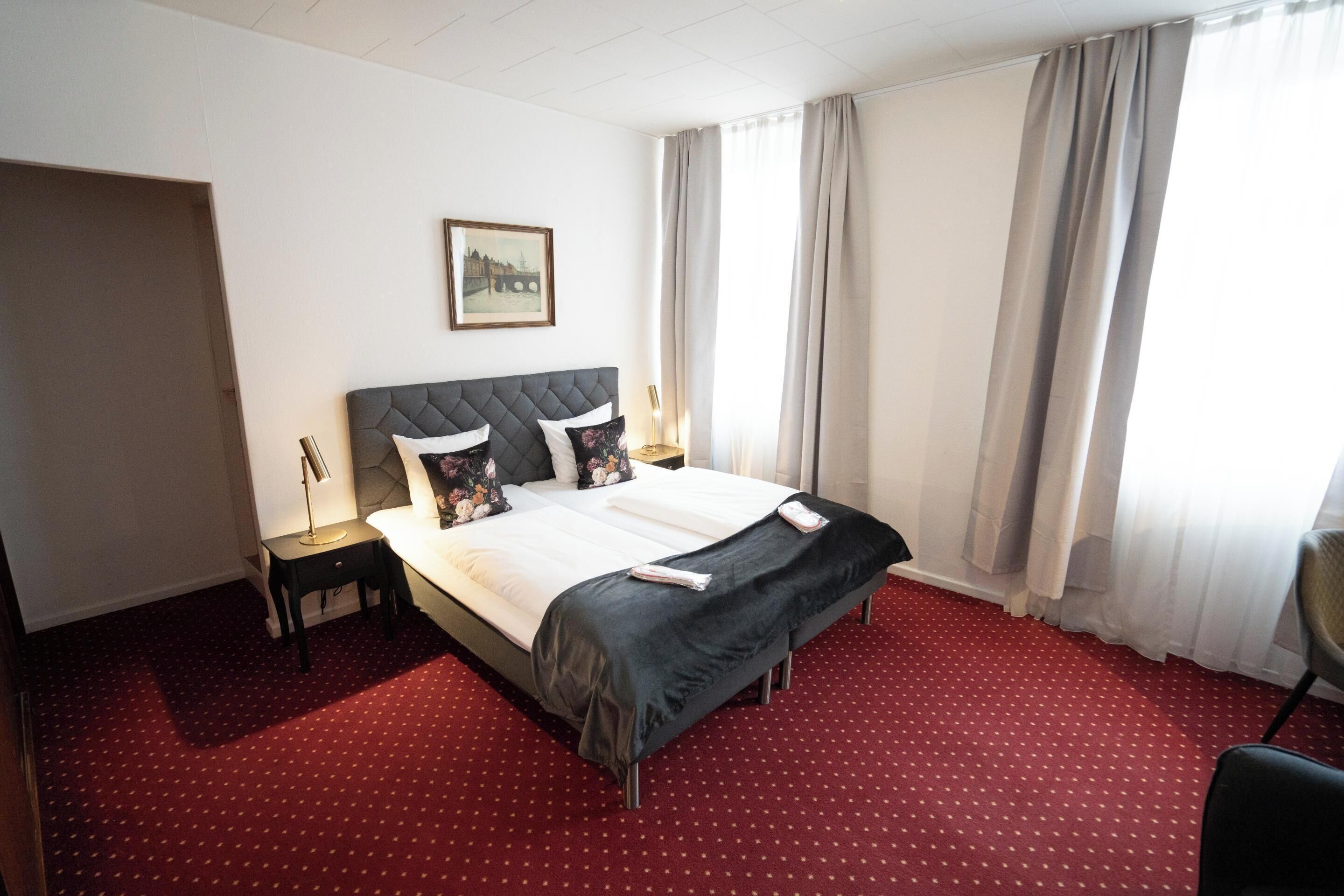 Una habitación de hotel con una cama grande, una mesita de noche, una lámpara y una silla.