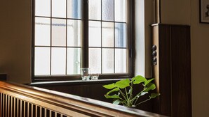 A window with a grid pattern and a plant on the sill. - Hotel Vinhuset (Naestved)