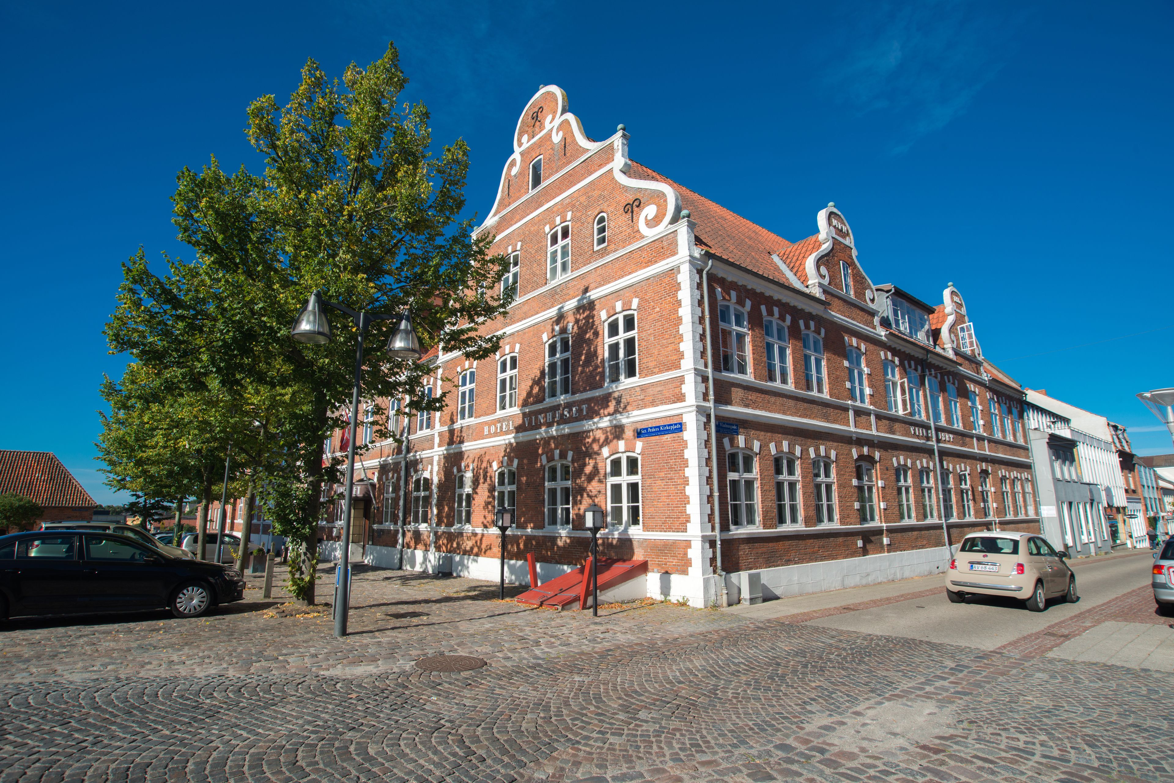 A historic building with a red brick facade, large windows, and a prominent clock tower.