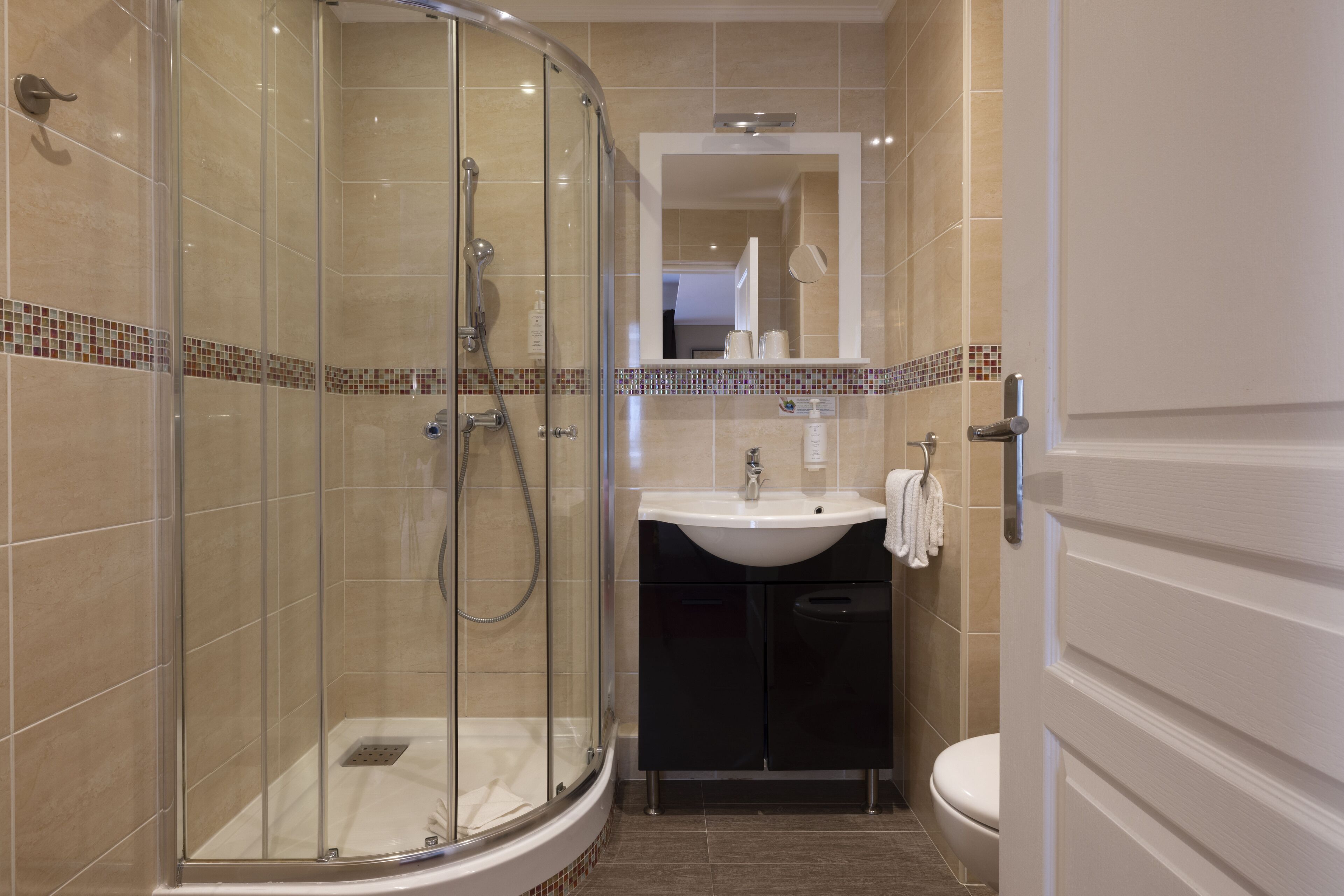 A modern bathroom with a glass-enclosed shower, a white sink, and a toilet.