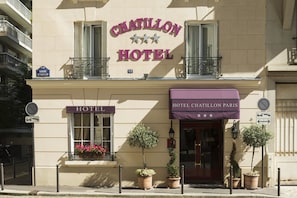 L’extérieur de l’hôtel Chatillon se distingue par une enseigne bien visible portant le nom de l’hôtel, un balcon orné de balustrades en fer forgé et des plantes en pot disposées devant l’entrée.