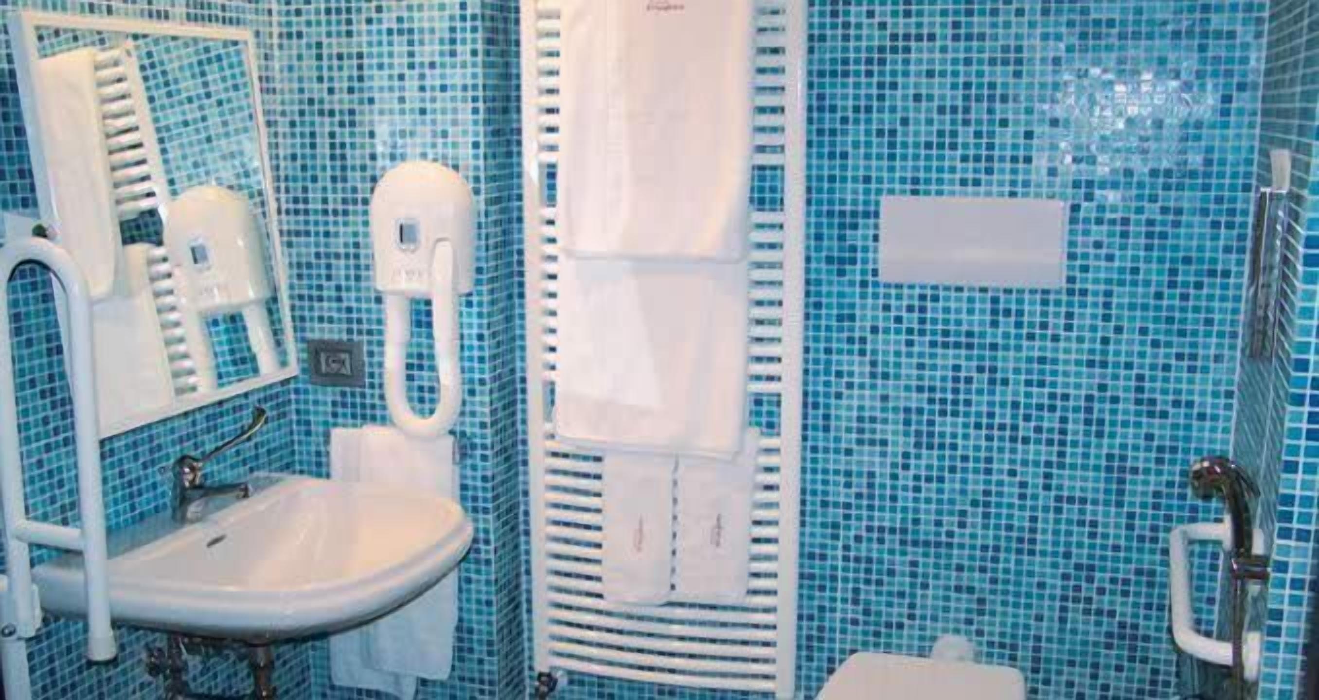 Un baño con lavamanos, espejo, toallero y zona de ducha.